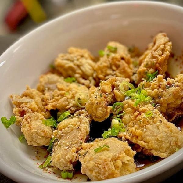Crispy fried chicken pieces with green onions and seasoning in a white bowl at Origami Restaurant.